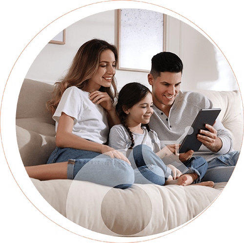 Familia sentada en el sofá mirando una tablet con internet eurona